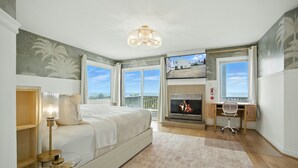 A bedroom with a bed, a desk, a fireplace, and a large window with a view. - On Beach 5BD+7BA: Sauna|HotTub|Billards|FencedDeck (Norfolk)