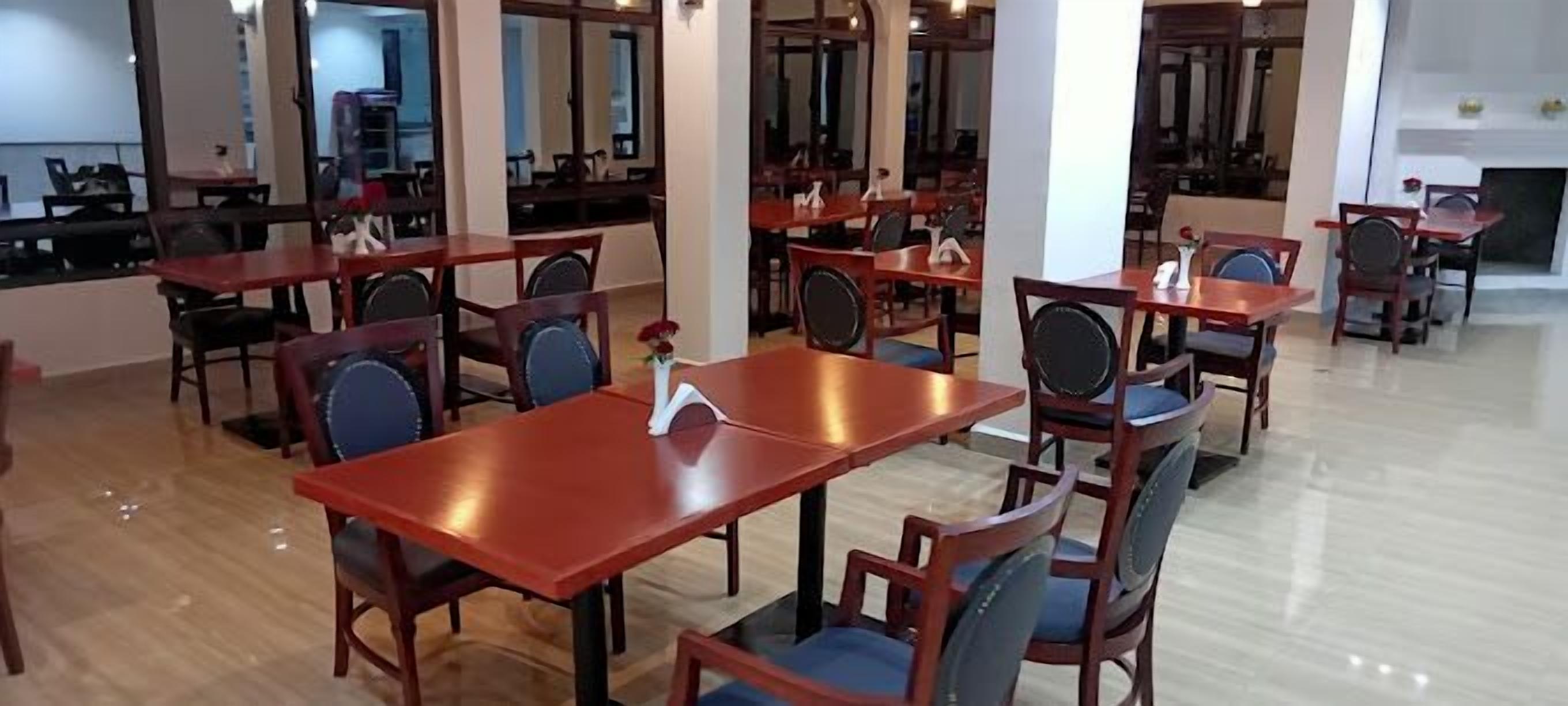 A spacious dining area with multiple wooden tables and chairs, arranged in a modern, open layout.