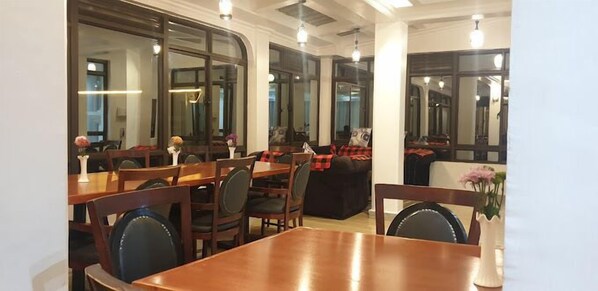 A restaurant with wooden tables and chairs, large windows, and a modern interior design. - Grand Tiara Hotel Naivasha (Naivasha)