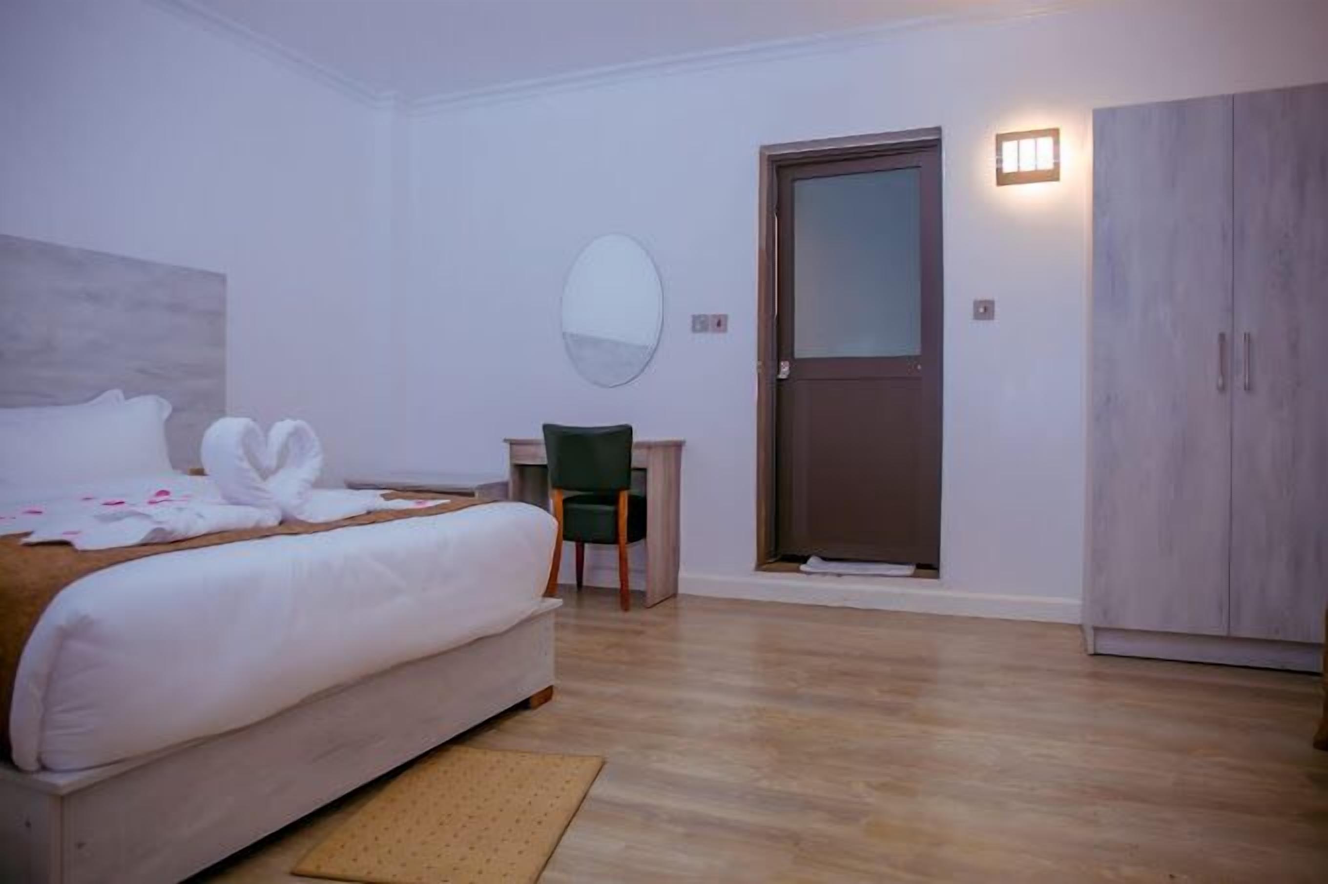 Una camera d'albergo con un letto, una scrivania, una sedia, un armadio e una porta.