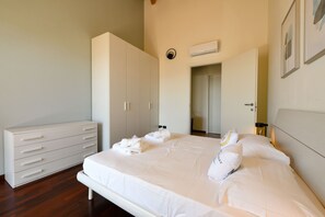 A bedroom with a bed, a dresser, a wardrobe, and an air conditioning unit.