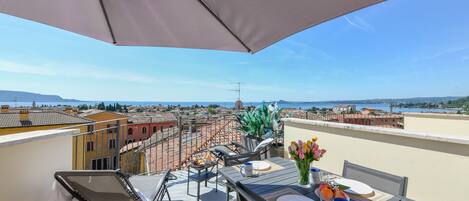 A rooftop terrace with a table set for two, a chair, and a view of the cityscape.