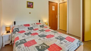 A bedroom with a bed, bedside lamps, a wooden door, and a small framed picture on the wall.