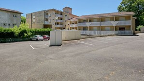 A multi-story building with balconies and a parking lot.