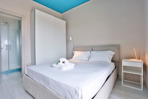 Un dormitorio con cama, mesita de noche, armario y lámpara en el techo.