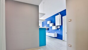 A modern interior with a hallway, light wooden flooring, a blue accent wall, and white built-in cabinets. - GuestHost - Vento di Mare House (Naples)