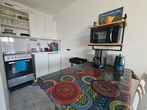 Eine kleine Küche mit Herd, Backofen, Mikrowelle und Kaffeemaschine.