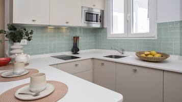 Een moderne keuken met witte kasten, een ingebouwde magnetron, een spoelbak en een raam.