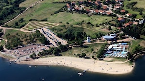 An aerial view of a coastal area with a beach, a parking lot, and a small village with houses.