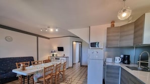 A compact kitchen with a dining area, a microwave, a refrigerator, and a sink.