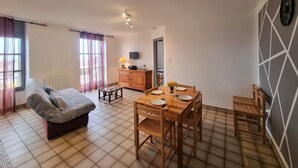 A compact living space with a sofa, a dining table with chairs, a TV, and a cabinet. - Family cottage in the heart of Côte Roannaise - Pets allowed (Saint-André-d'Apchon)