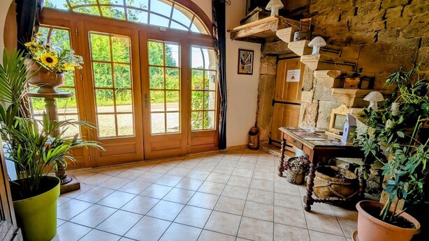 A rustic interior with a large arched wooden door, tiled floor, and stone walls. - Spacious house with spa, ping-pong, and foosball, perfect for family relaxation (La Chapelle-aux-Bois)