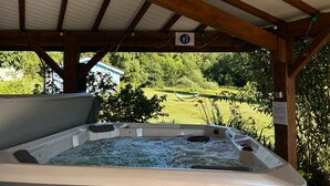 A hot tub under a wooden pergola with a view of a grassy area and trees. - Spacious house with spa, ping-pong, and foosball, perfect for family relaxation (La Chapelle-aux-Bois)