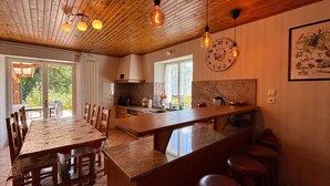 A spacious kitchen with a wooden ceiling, a large island with stools, and a dining area with chairs. - Spacious house with spa, ping-pong, and foosball, perfect for family relaxation (La Chapelle-aux-Bois)