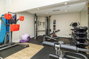 Een sportschool met diverse trainingsapparaten, waaronder een loopband, krachttoestellen en gewichten.