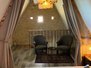 A cozy room with a sloped ceiling, two chairs, a small table, and a patterned rug.