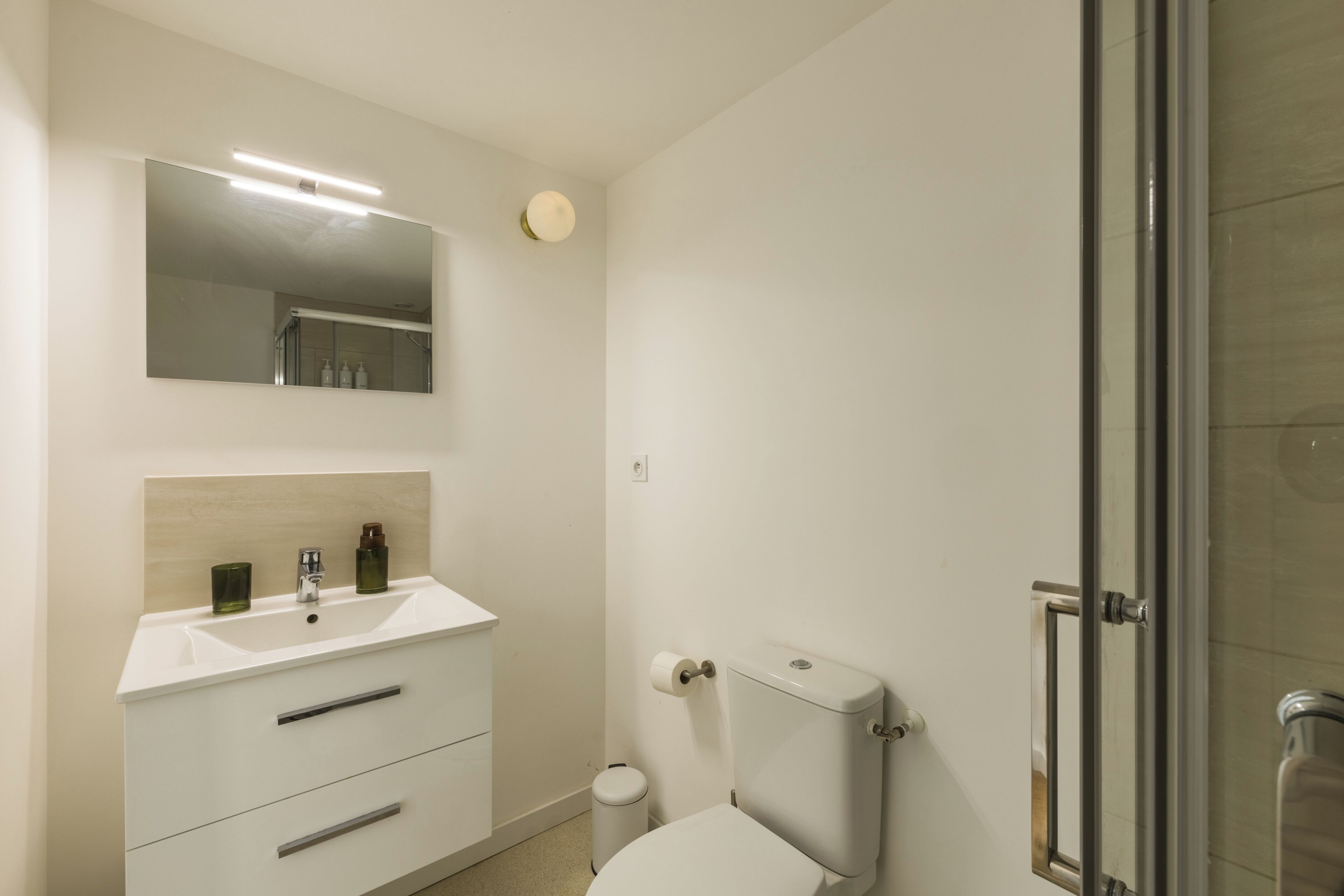 A bathroom with a white sink, mirror, and toilet.