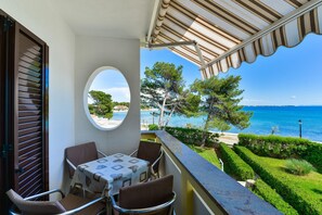 Varanda com mesa e cadeiras, vista para uma piscina e o mar.