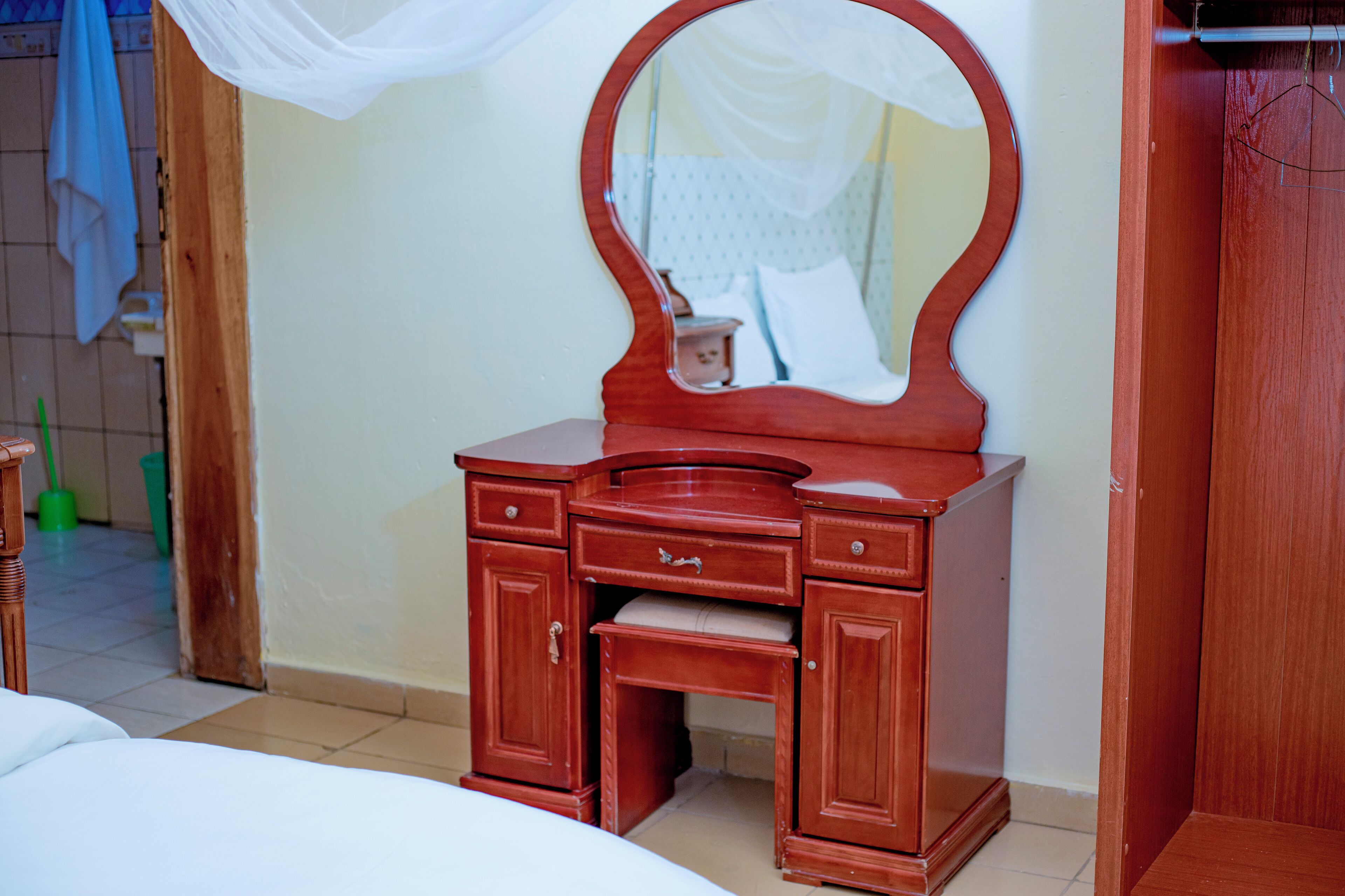 A wooden vanity with a mirror, drawers, and a bench.