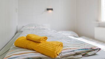 A single bed with a striped bedspread and two rolled-up towels.