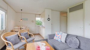 A cozy living area with a grey sofa, wicker chairs, and a wooden table with candles.