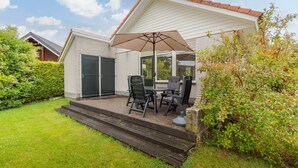 A patio with a table and chairs, a large umbrella, and a brick wall.