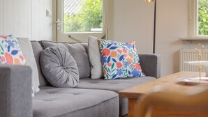 A cozy living room with a grey sofa, floral cushions, and a wooden coffee table.
