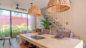A modern kitchen with a large island, hanging wicker lights, and a staircase leading to an upper level. - Calixto 03 | Walk to Beach | Modern Design | Pool | Kitchen | Garden Oasis | Tranquil Setting (Bucerias)