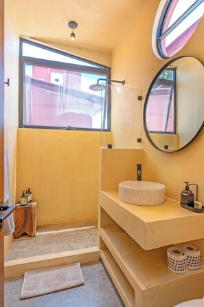 Een badkamer met een ronde spiegel, een wastafel en een douche.