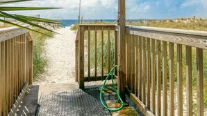 A wooden boardwalk leading to a beach with a metal lamp post and a hose on the ground. - Seacrest 202 | Gulf-Front Condo w/ Balcony (Gulf Shores)