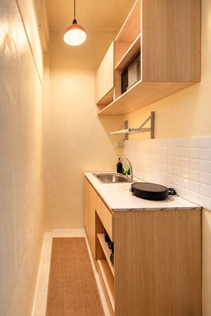 Una cocina estrecha con armarios de madera, una encimera, un fregadero y una lámpara colgante.