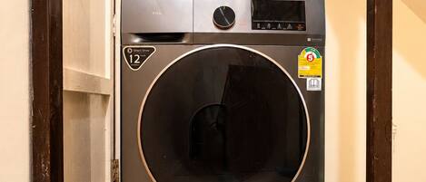 A compact, modern washing machine in a narrow hallway with a tiled floor.
