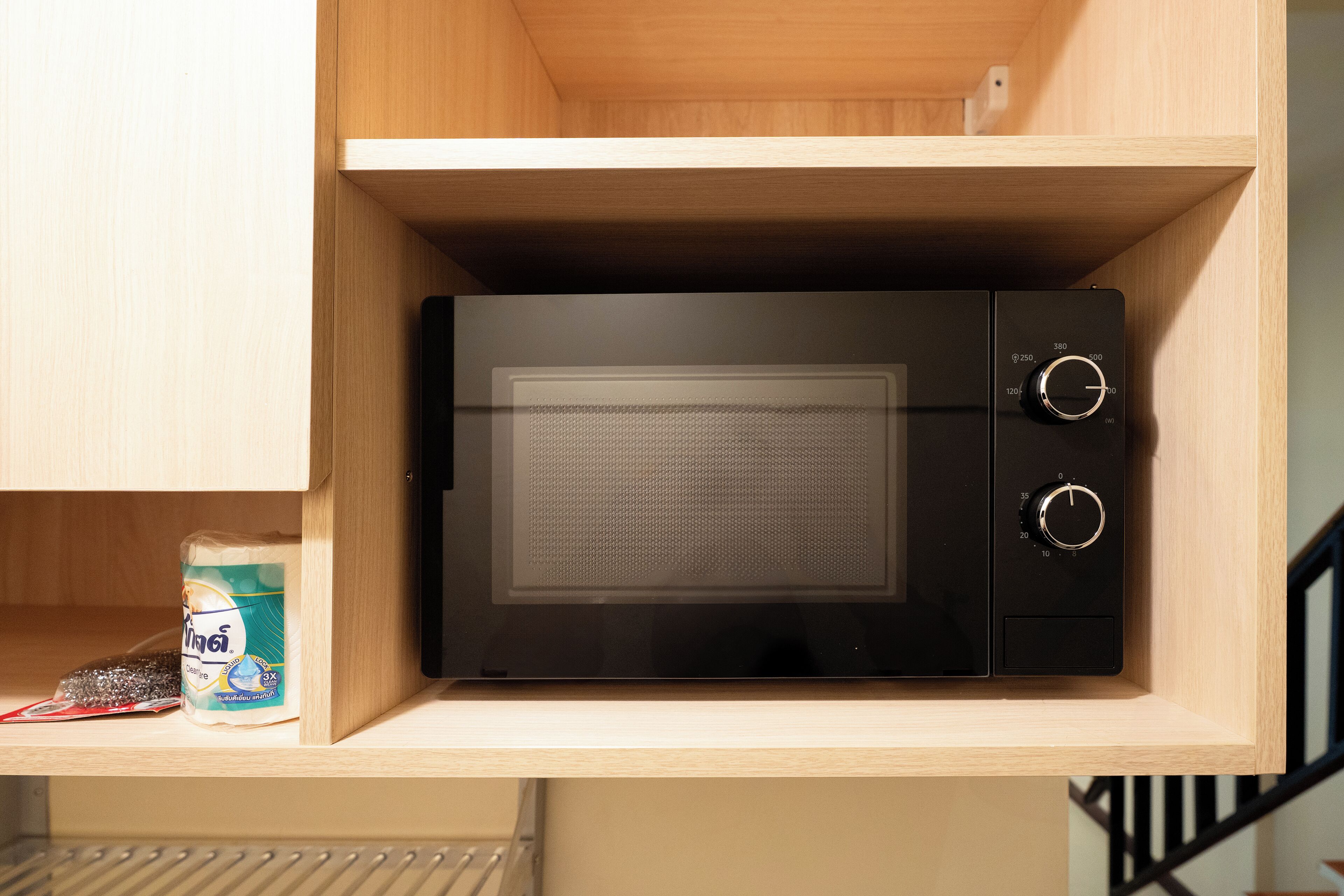 Un four à micro-ondes intégré dans un meuble en bois, doté d’un panneau de commande.