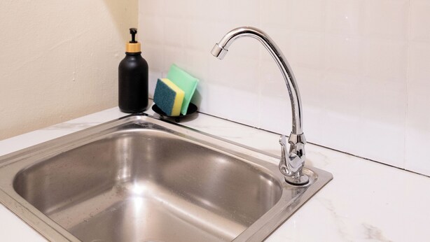 A kitchen with a stainless steel sink, a faucet, a soap dispenser, and a sponge holder. - House in Khao San - OH Homes Samsen 10 (Bangkok)