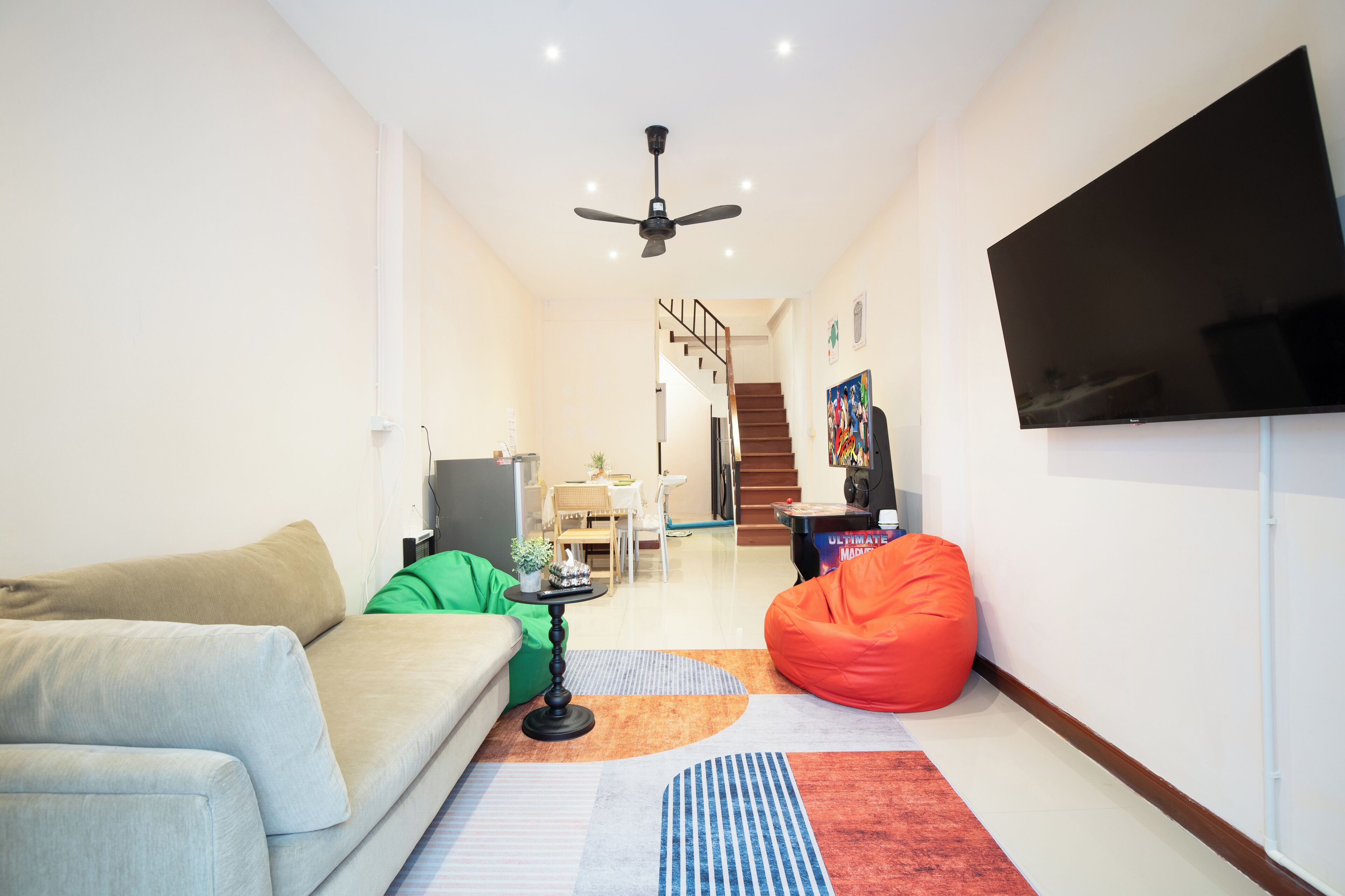 Ein modernes Wohnzimmer mit einer Couch, einem Sitzsack, einem Couchtisch und einem an der Wand befestigten Flachbildfernseher.