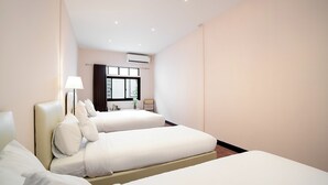 A hotel room with two beds, a window, and a desk with a lamp. - House in Khao San - OH Homes Samsen 12 (Bangkok)