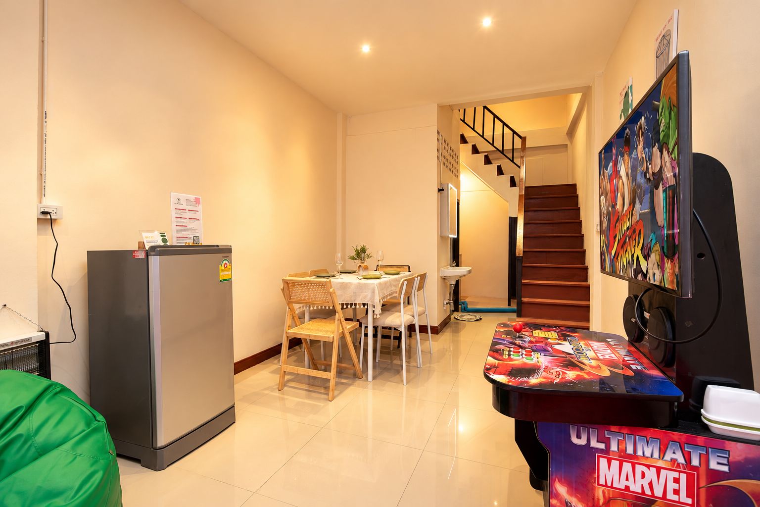 Ein Hotelzimmer mit Essbereich, einem Kühlschrank, einem Tisch mit Marvel-Motiv und einer Treppe.