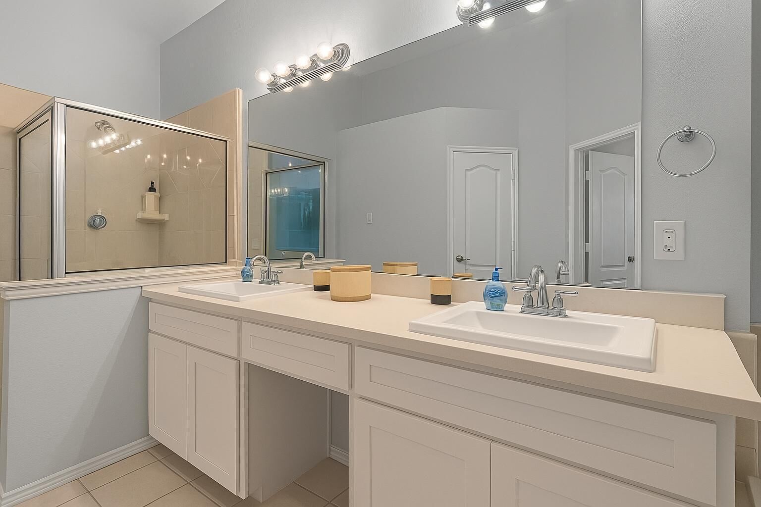 A modern bathroom with two sinks, a large mirror, and a shower.
