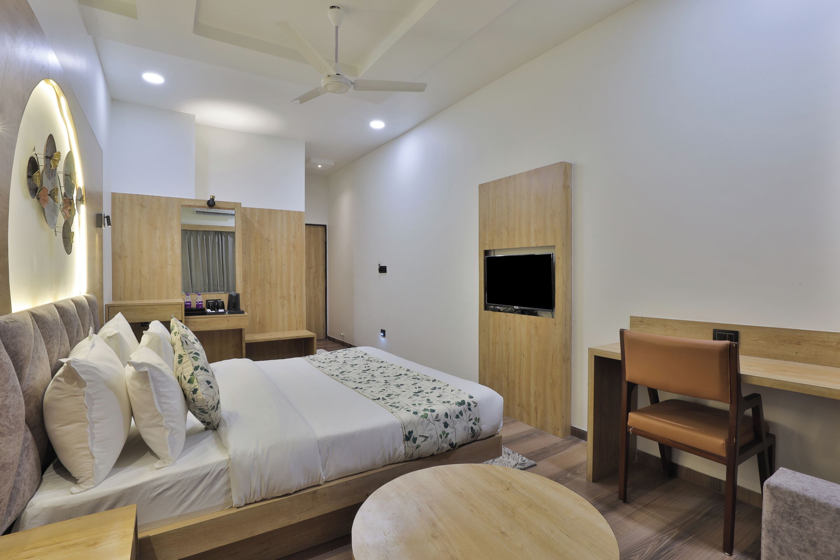 A modern bedroom with a bed, a desk, a chair, and a TV.