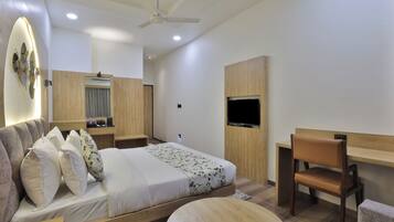 A modern bedroom with a bed, a desk, a chair, and a TV.