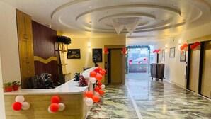 A reception area with a marble floor, a reception desk, and a wall-mounted wooden panel. - Hotel SR Laxmi (Anand)