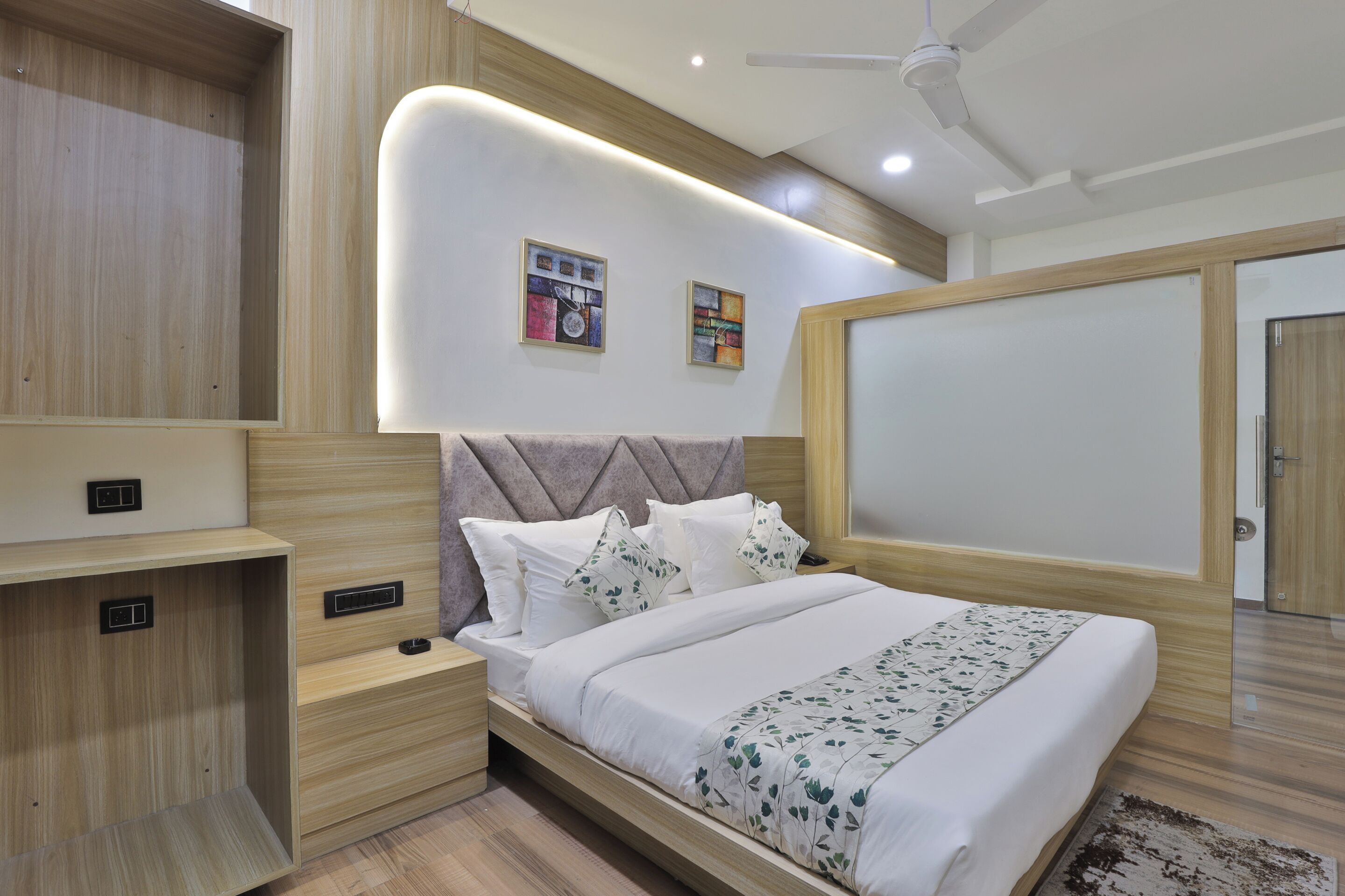 A modern bedroom with a bed, bedside tables, a ceiling fan, and wall-mounted artwork.