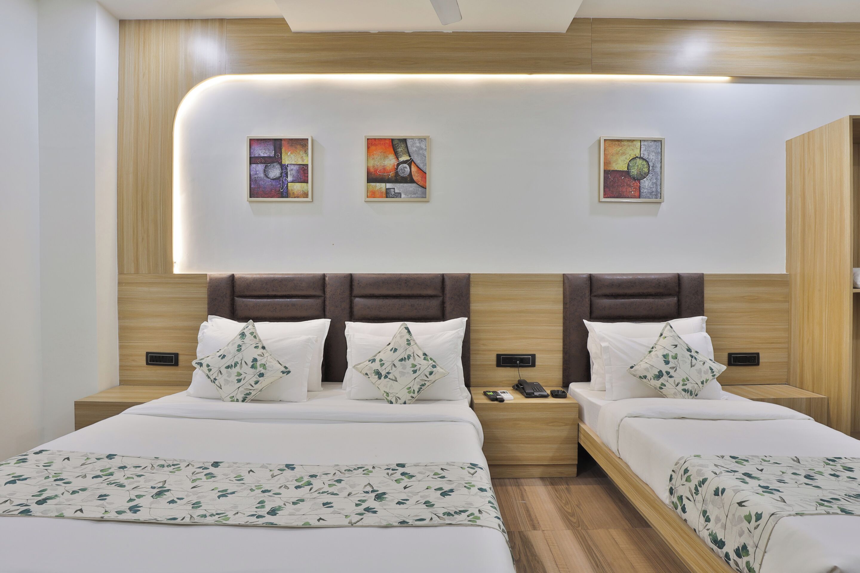 Habitación de hotel con dos camas, cabecero de madera y obras de arte en la pared.