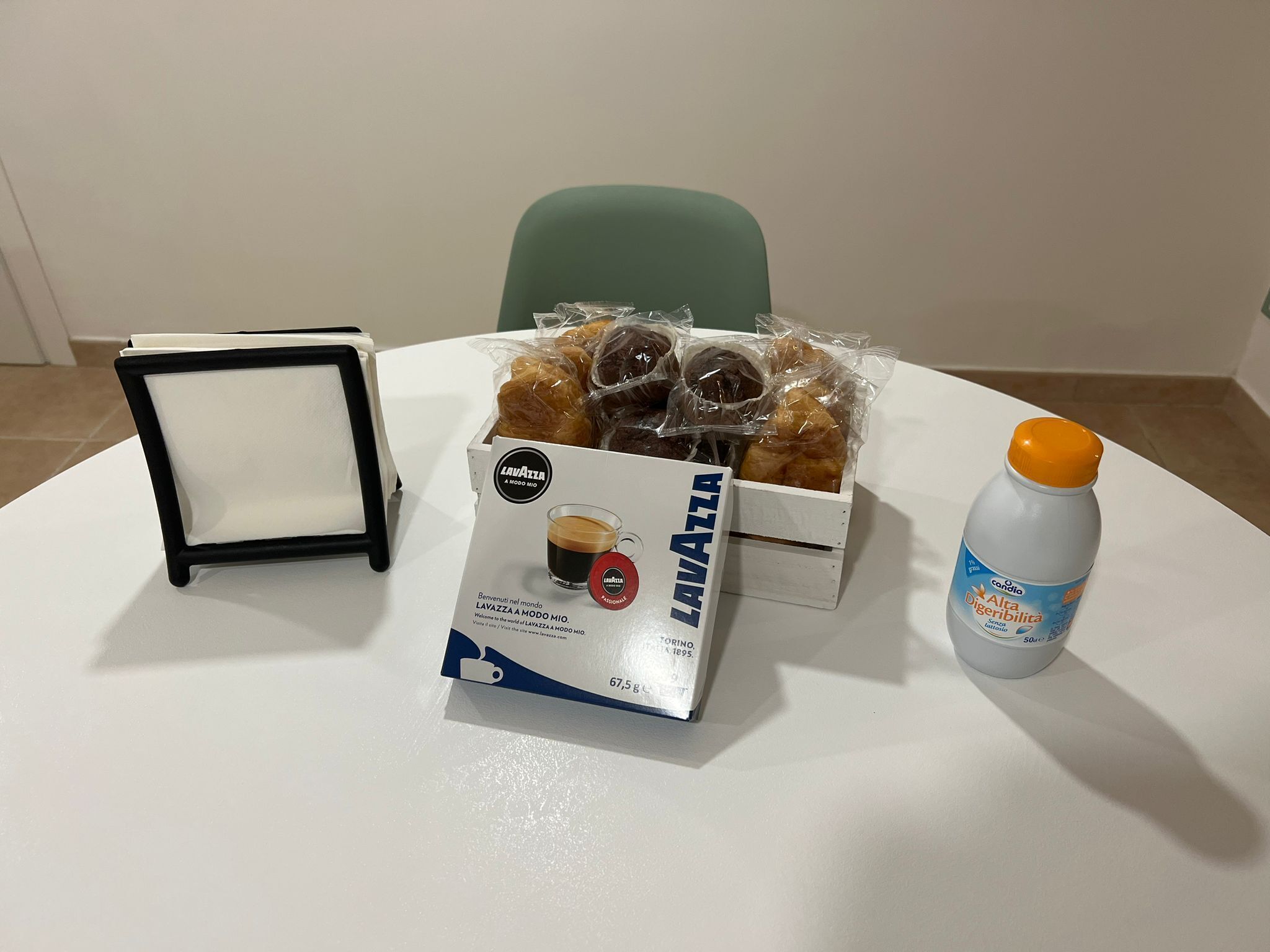A table with a box of Lavazza coffee, a bottle of water, and a tray of pastries.