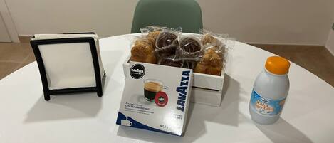 A table with a box of Lavazza coffee, a bottle of water, and a tray of pastries.