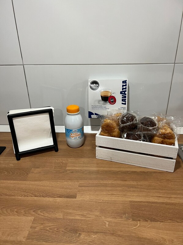 Una pequeña mesa con un marco, una botella de Alto Digitalis y una caja de café Lavazza.
