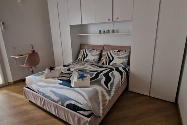 A bedroom with a bed, a bedside table, a chair, and a wardrobe.