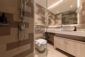 Une salle de bain moderne avec une douche à parois de verre, des toilettes blanches et un meuble-lavabo doté d’un miroir et d’un évier.