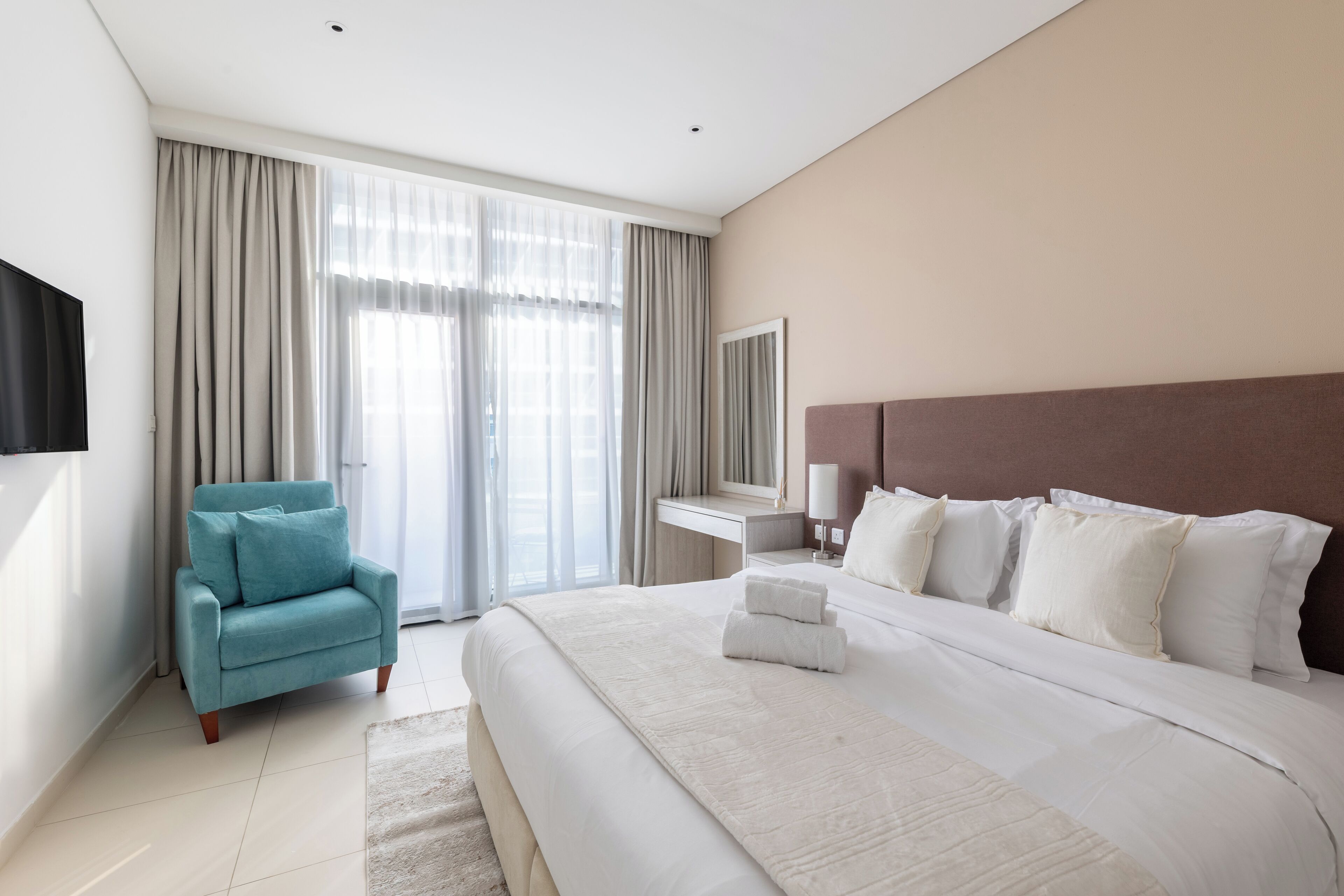 Una habitación de hotel moderna con una cama grande, un escritorio, una silla y un televisor.