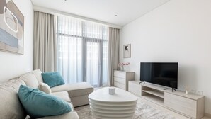 A modern living room with a sofa, ottoman, coffee table, TV, and a minimalist decor.